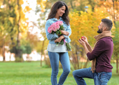 a young man proposing to a woman in a park