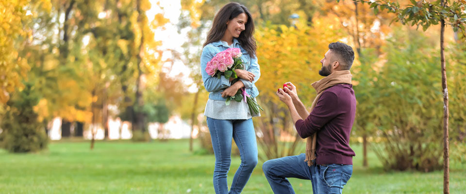 a young man proposing to a woman in a park